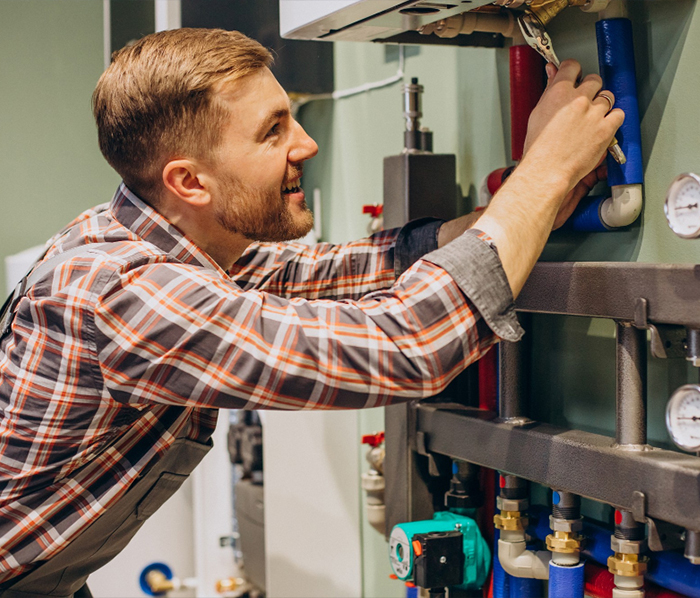 Plumber inspecting and repairing boiler system components with colorful pipes and gauges in Bordentown, NJ.
