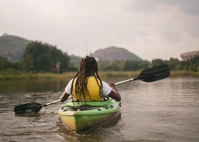 Person kayaking on a lake surrounded by greenery and hills, showcasing recreational activities available at Mercer County Park in Hamilton, NJ.