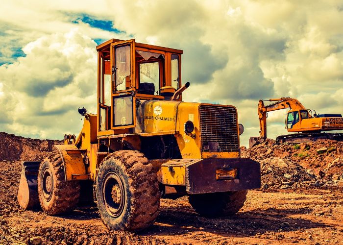 Yellow construction vehicle in a dirt field, showcasing heavy equipment featured at Diggerland USA amusement park in West Berlin, New Jersey.