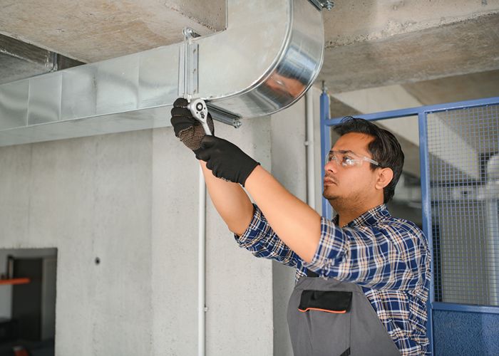 HVAC technician wearing safety glasses and gloves during air conditioning system setup.