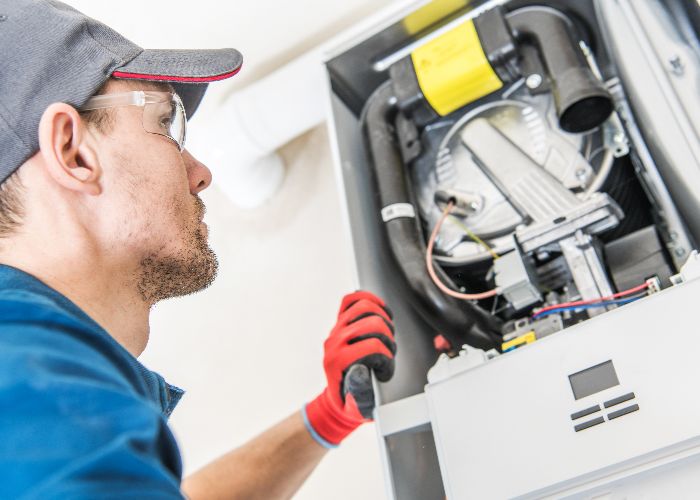 Technician inspecting a heating system, wearing gloves and safety glasses, emphasizing professional heating repair services in New Jersey.
